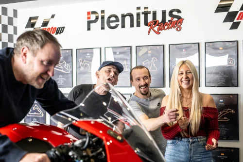 Group enjoying the Plenitus Racing Sim experience with a motorcycle on display