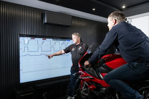 Instructor reviewing telemetry data with a rider on the Plenitus Racing Sim